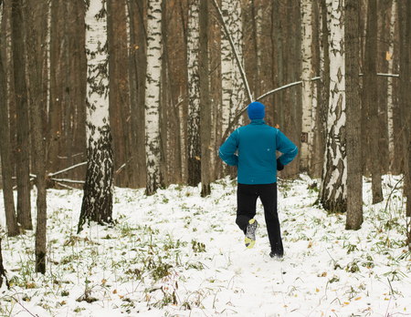 The man likes to run in the winter forest. Healthy lifestyle concept. Running in the winter forest.の写真素材