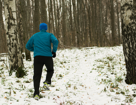 The man likes to run in the winter forest. Healthy lifestyle concept. Running in the winter forest.の写真素材