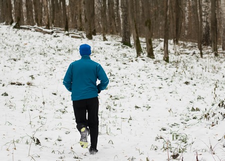 The man likes to run in the winter forest. Healthy lifestyle concept. Running in the winter forest.の写真素材