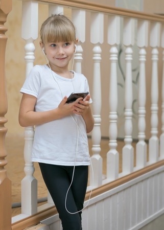 Portrait of a beautiful girl in a wooden fence. Listening to music through your smartphone.の写真素材