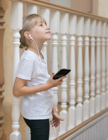 Portrait of a beautiful girl in a wooden fence. Listening to music through your smartphone.の写真素材