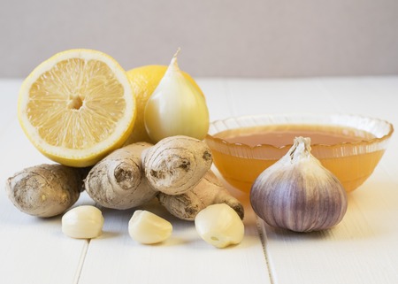 The root of ginger and honey on white wooden table. The concept of treatment with natural products.の写真素材