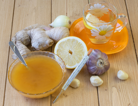 The root of ginger, lemon, garlic, onion and honey on wooden table. The concept of treatment with natural products.の写真素材