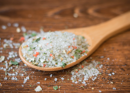 Spoon with coarse sea salt and spices on a wooden table. Universal set of spices for cooking.の写真素材
