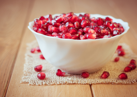 Pomegranate seeds in a bowl on a wooden table. Ripe fruit of a pomegranate. Fruit diet. Healthy lifestyle concept.の写真素材