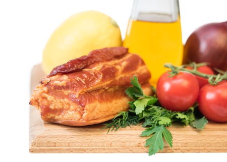 Smoked pork with spices on a wooden board isolated on white background. Still life of meat dishes.