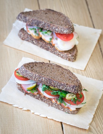 Fresh sandwich on a wooden table with a piece of burlap. Fast food concept.の写真素材