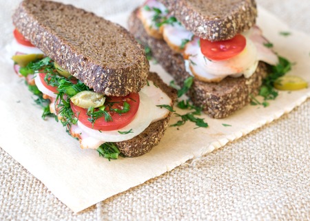 Fresh sandwich on a wooden table with a piece of burlap. Fast food concept.の写真素材