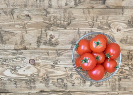 Cherry tomatoes in a bowl of glass on a rustic table. Healthy food concept.の写真素材