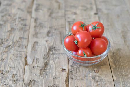 Cherry tomatoes in a bowl of glass on a rustic table. Healthy food concept.の写真素材
