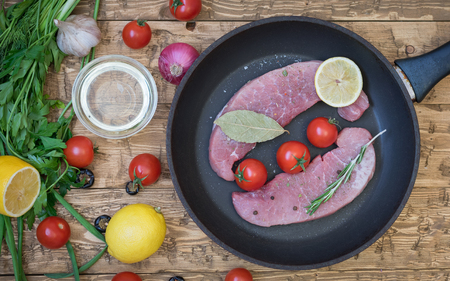 Raw pork on a frying pan on a rustic table. Ingredients for the preparation of meat dishes. Home kitchen.の写真素材