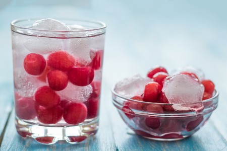 Cold water with ice, cherries and berries. Vintage background. A refreshing drink for a healthy diet.の写真素材