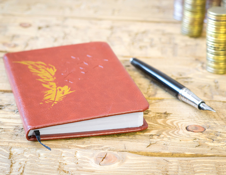 Fountain pen, coins and notebook on a wooden table. Business still-life. The concept of budget allocation.の写真素材