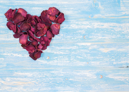 Rose petals in a heart shape on the vintage wooden table. The concept of love heart.の写真素材