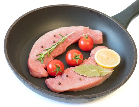 Raw pork on a frying pan isolated on white background. Ingredients for the preparation of meat dishes. Home kitchen.の写真素材