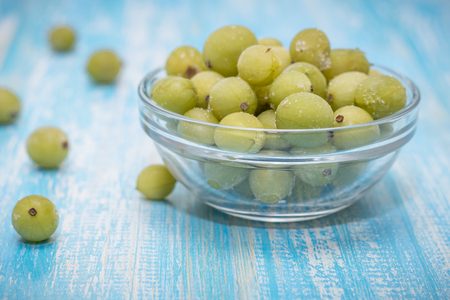 Frozen berries gooseberries in a bowl of glass on vintage table. Healthy vegetarian food. Dietary product.の写真素材