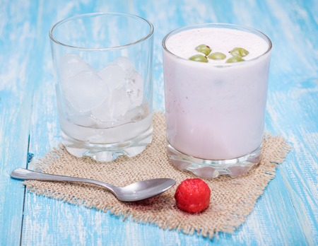 Milkshake with strawberries, gooseberries and ice on a blue table.Healthy lifestyle concept. Sports nutrition.の写真素材
