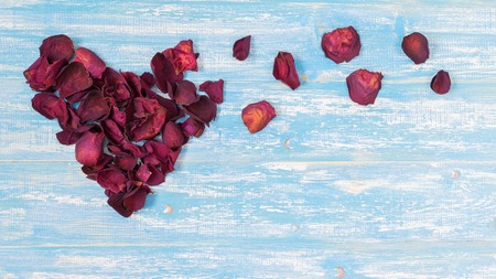 Rose petals in a heart shape on the vintage wooden table. The concept of love heart.の写真素材