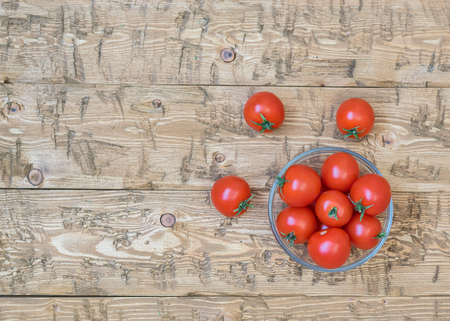 Cherry tomatoes in a bowl of glass on a rustic table. Healthy food concept. Top view.の写真素材