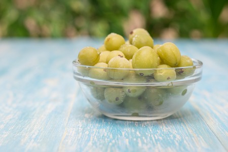 Frozen berries gooseberries in a bowl of glass on vintage table. Healthy vegetarian food. Dietary product.の写真素材