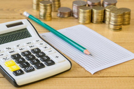Metal coins and calculator on a rustic table. The concept of a home workplace. Family budget.の写真素材