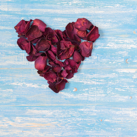 Rose petals in a heart shape on the vintage wooden table. The concept of love heart.の写真素材