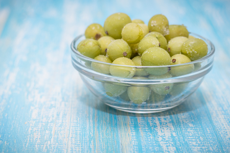 Frozen berries gooseberries in a bowl of glass on vintage table. Healthy vegetarian food. Dietary product.の写真素材