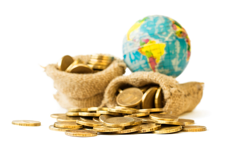 Metal coins and globe isolated on white background. The concept of budget travel. Money rules the world.の写真素材