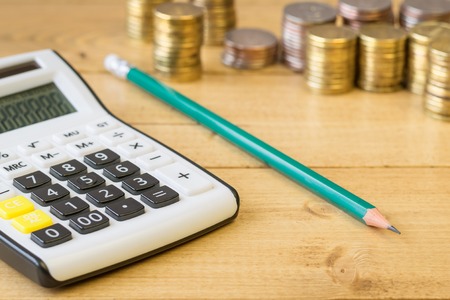 Metal coins and calculator on a rustic table. The concept of a home workplace. Family budget. Planning costs and revenues.の写真素材