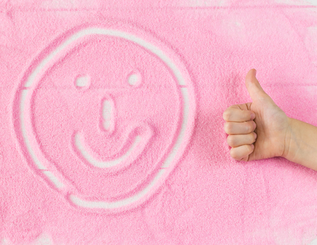 Funny mug of decorative sand and a child's hand. The concept of children's educational activities.の写真素材