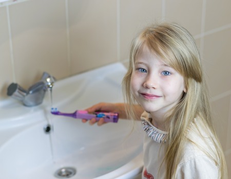 A little girl is brushing her teeth with an electric toothbrush. The concept of oral care.の写真素材