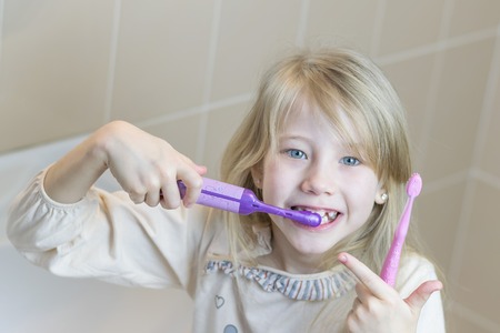 The girl is holding an electric toothbrush in her hand. The concept of oral care.の写真素材
