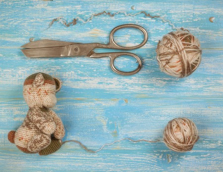 Unfinished knitted multi-colored toy on a wooden table.The concept of home handicraft.の写真素材