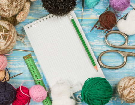 Scissors, balls of wool, measuring tape and notebook on a wooden table. The concept of home handicraft.の写真素材