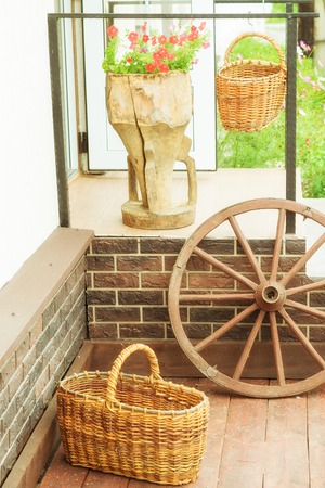 Wheel, basket and flowers on the porch classic facade. The concept of comfortable private dwellings.の写真素材
