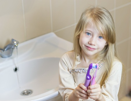 Two different toothbrushes kiss the girl in his hands. The concept of oral care.の写真素材