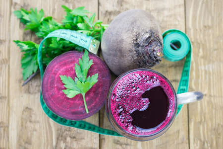 Beet juice with parsley and measuring tape on a wooden table. View from above. The concept of a healthy vegetarian diet.の写真素材