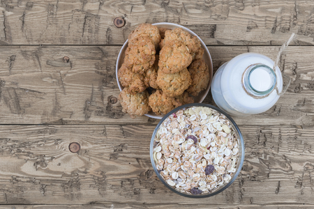 Bowl with homemade cookies, bottle of milk and muesli on brown wooden table. Diet organic Breakfast. Top viewの写真素材