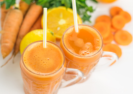 Two glass mugs with a carrot smoothie on a white wooden table. The concept diet food for weight loss. Top view.の写真素材