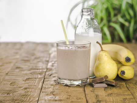 Banana smoothie with chocolate, pear and milk on a wooden table. The concept of a healthy diet.の写真素材