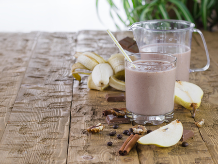 Banana smoothie with chocolate, pear and milk on a wooden table. The concept of a healthy diet.の写真素材