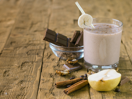 Banana smoothie with chocolate, pear and milk on a wooden table. The concept of a healthy diet.の写真素材