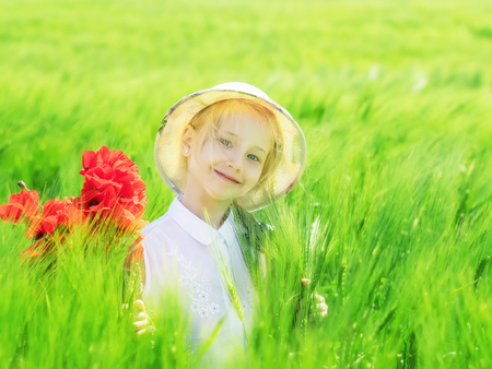 Happy little girl in a field of green rye. Portrait girl on nature background.の写真素材