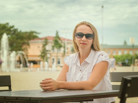 Woman in sunglasses at a table in summer cafe.の写真素材