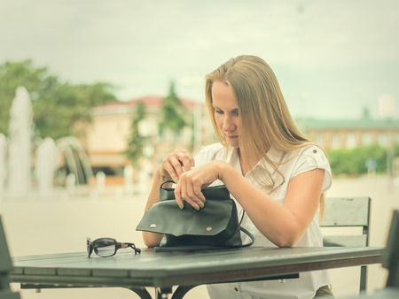 Woman in sunglasses at a table in summer cafe. Portrait of a beautiful woman on the background of the town square.の写真素材