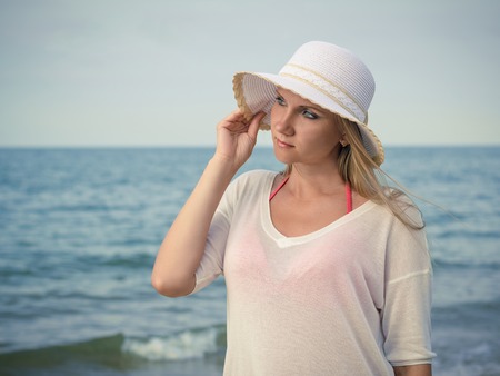 Beautiful woman on a sandy beach at sunset. Portrait of a beautiful woman by the ocean.の写真素材