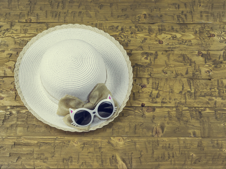 Women's hat, sun hat and glasses on a wooden table. The concept accessories for a summer vacation.の写真素材