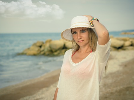 Woman in hat with multi-colored bracelets on the beach. Portrait of a beautiful woman by the ocean.の写真素材