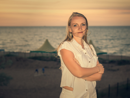 Beautiful woman on a sandy beach at sunset. Portrait of a beautiful woman by the ocean.の写真素材