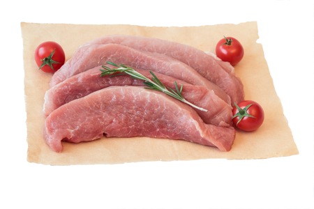 Pieces of raw pork with tomatoes on paper isolated on white background. Fresh pork meat for cooking delicious roast.の写真素材